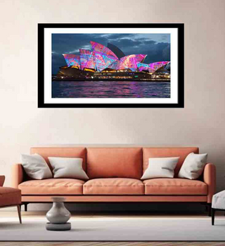 Framed artwork of a colorful Sydney Opera House on a wall above a red sofa.